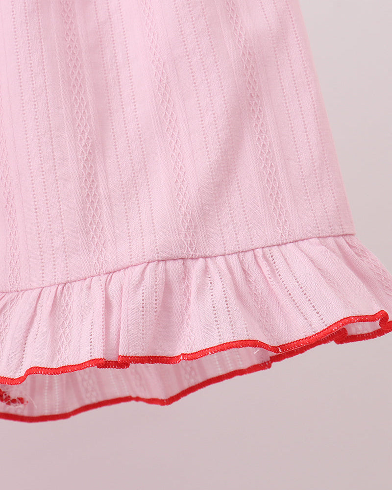 Close-up of a pink dress with red trim on a light gray background