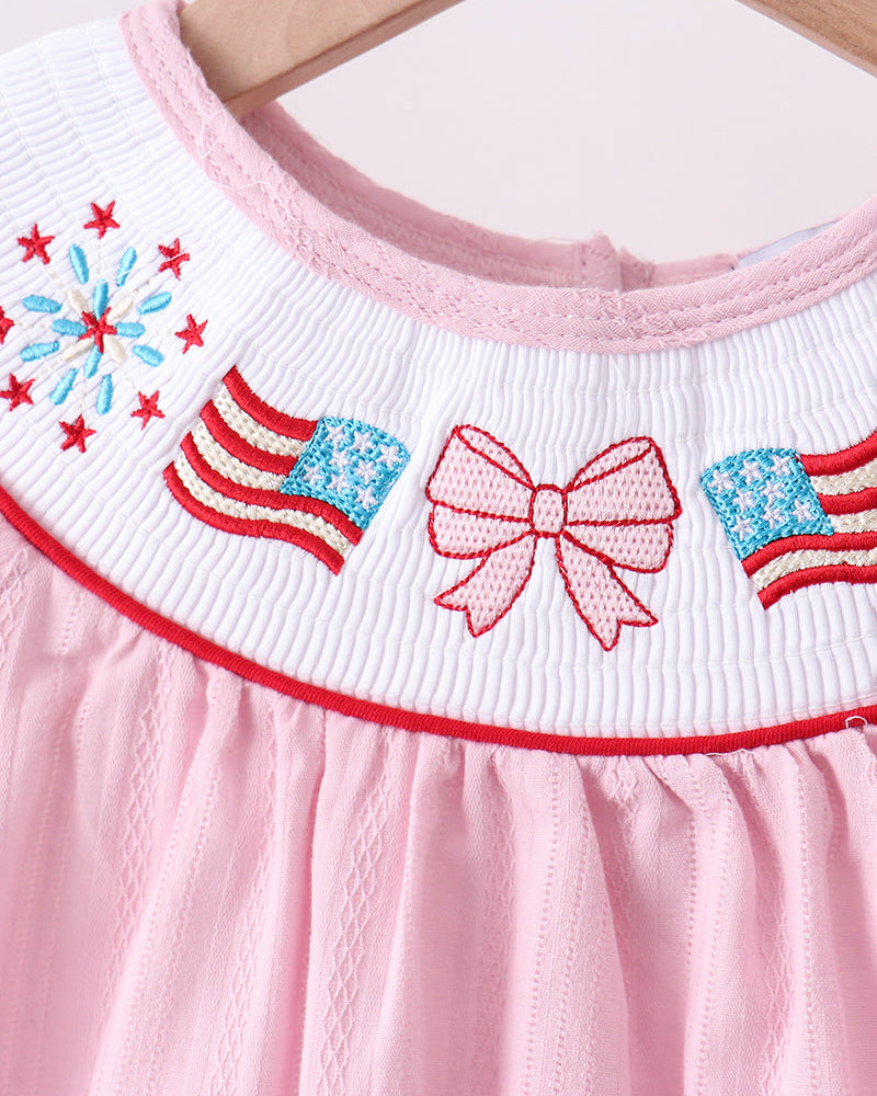 Pink dress with American flag and bow design on a wooden hanger