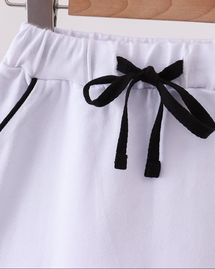 White bow skort with scalloped hem and black ribbon ties at the waist