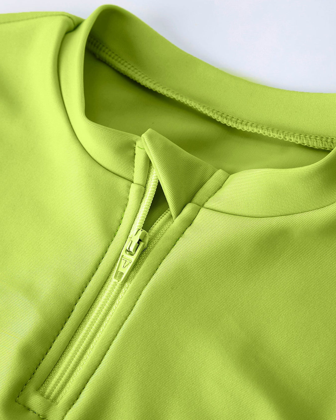 Close-up of a green swim top with a zipper on a white background