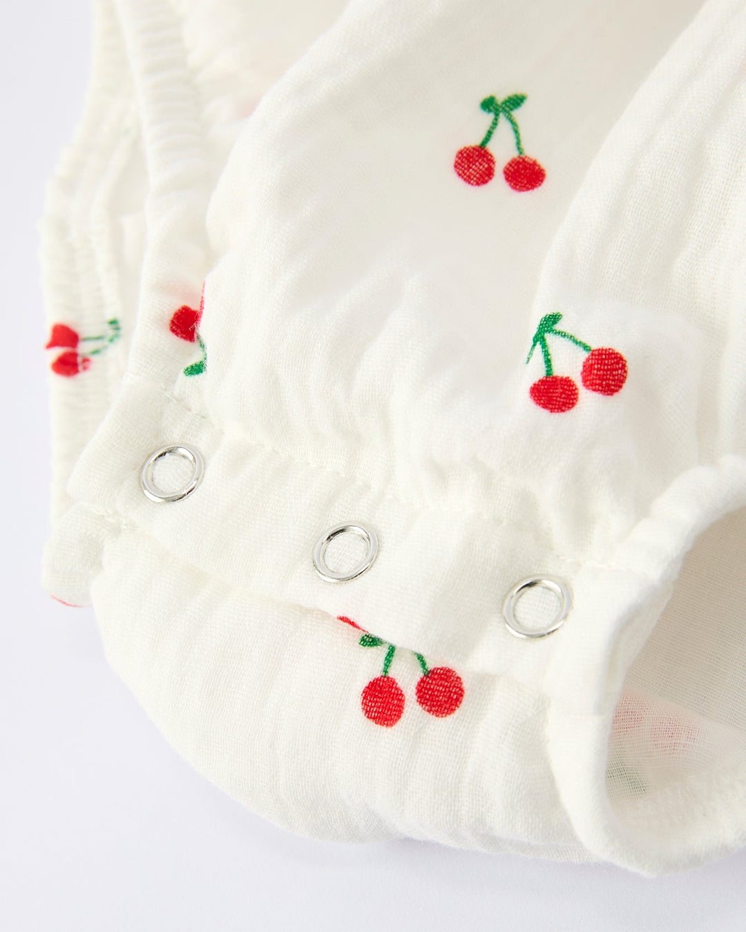 White baby bibs with cherry embroidery on a light gray background