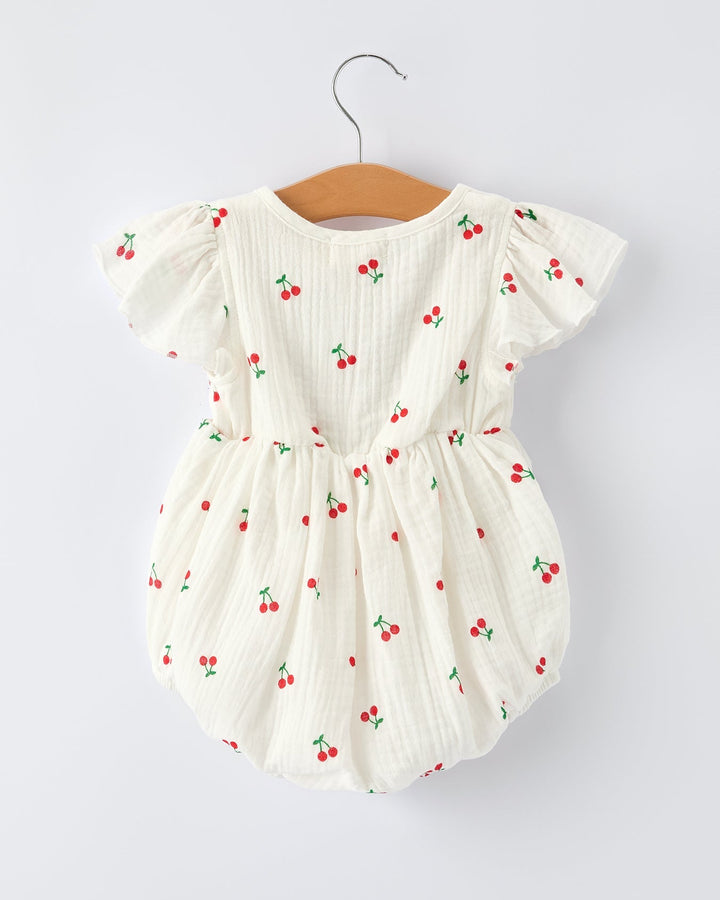 White baby romper with red cherry pattern on a white background