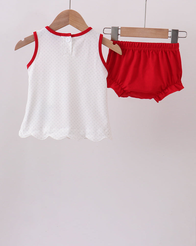 White sleeveless top with red trim and red bloomers hanging on wooden hangers against a light gray background.