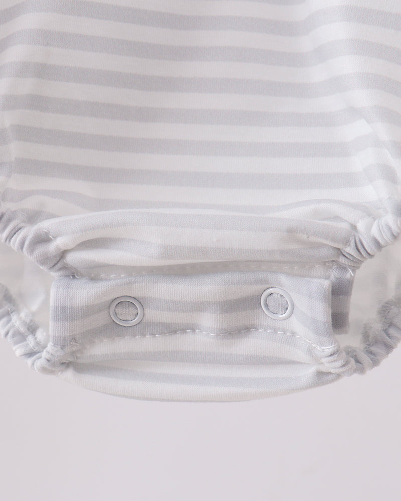 Close-up of a white baby romper with a button on a light gray background