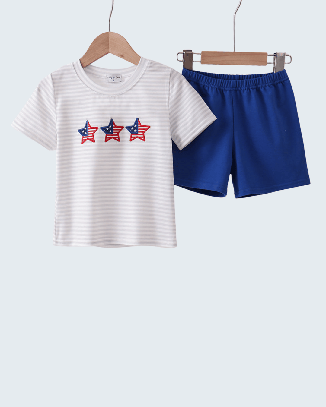 Children's t-shirt with star design and blue shorts on hangers against a white background