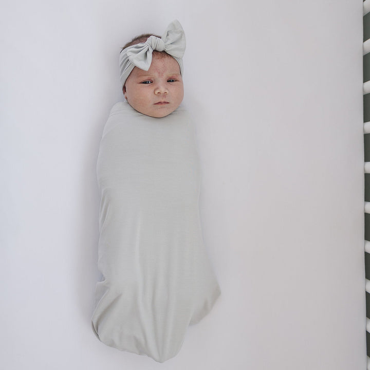 Light gray bamboo head wrap with knotted bow, worn by baby
