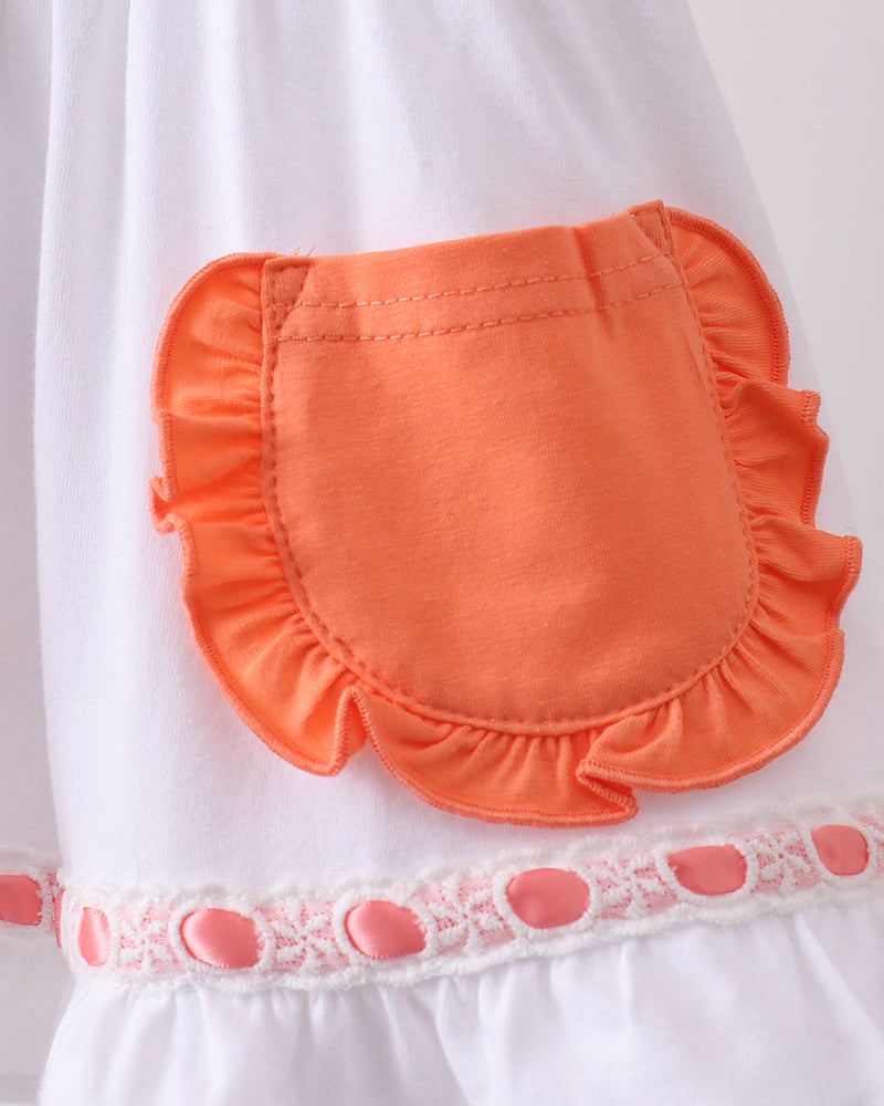 Orange pocket on a white garment with lace trim