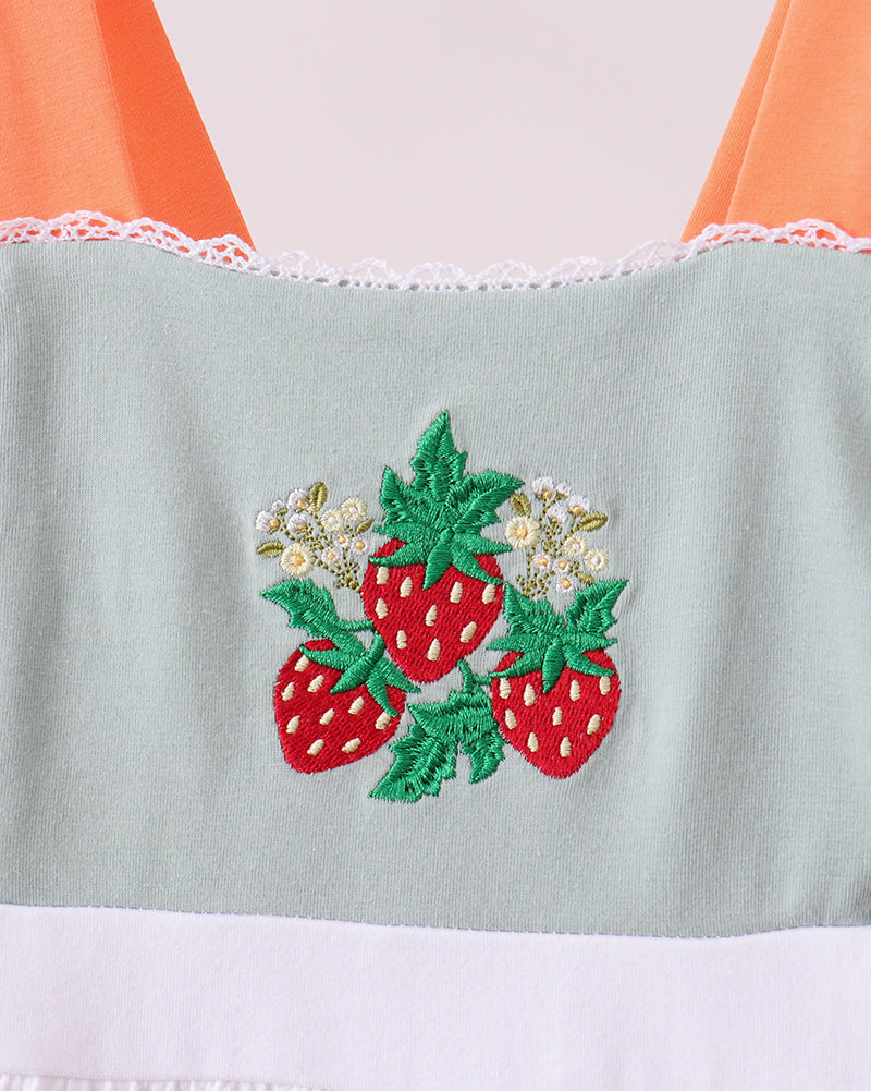 Dress with strawberry embroidery on a light green section against an orange and white background