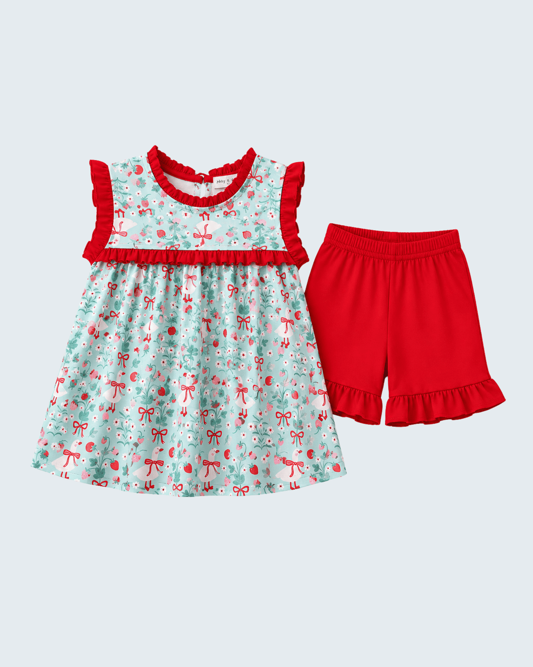 Children's outfit with a dress and red shorts on a light gray background