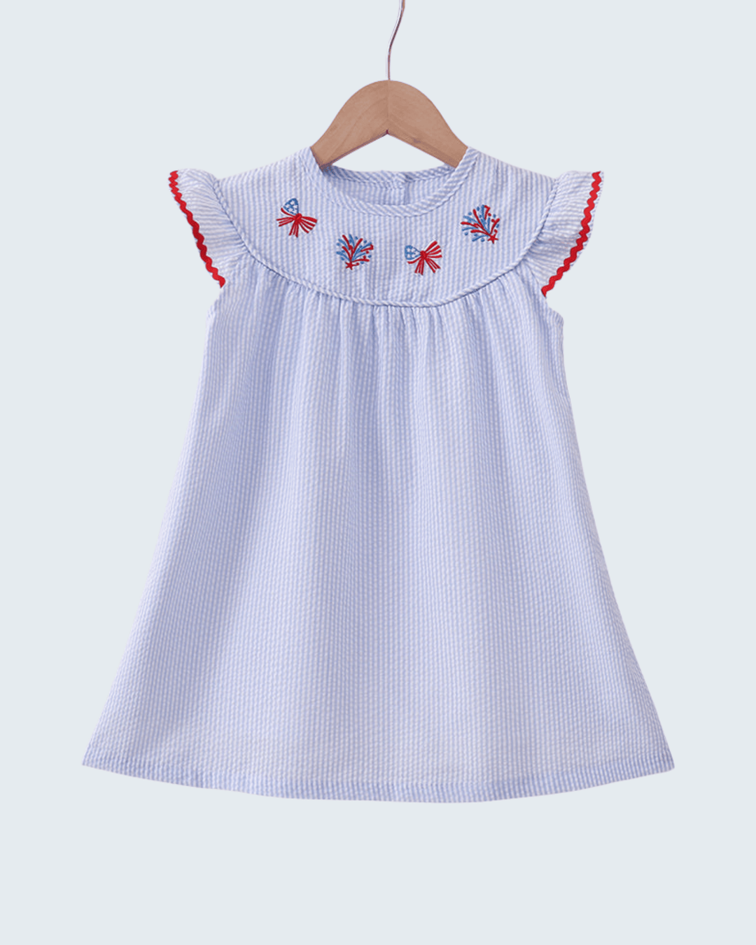 Children's dress with red trim and floral embroidery on a white background