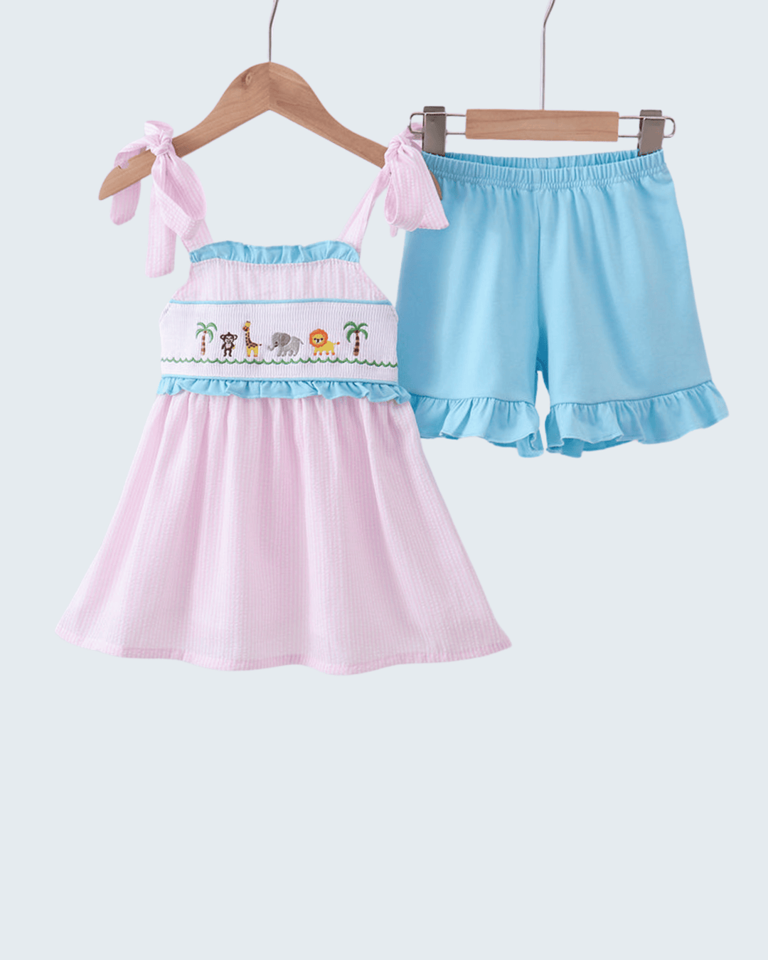 Pink dress with ruffled shorts on hangers against a white background