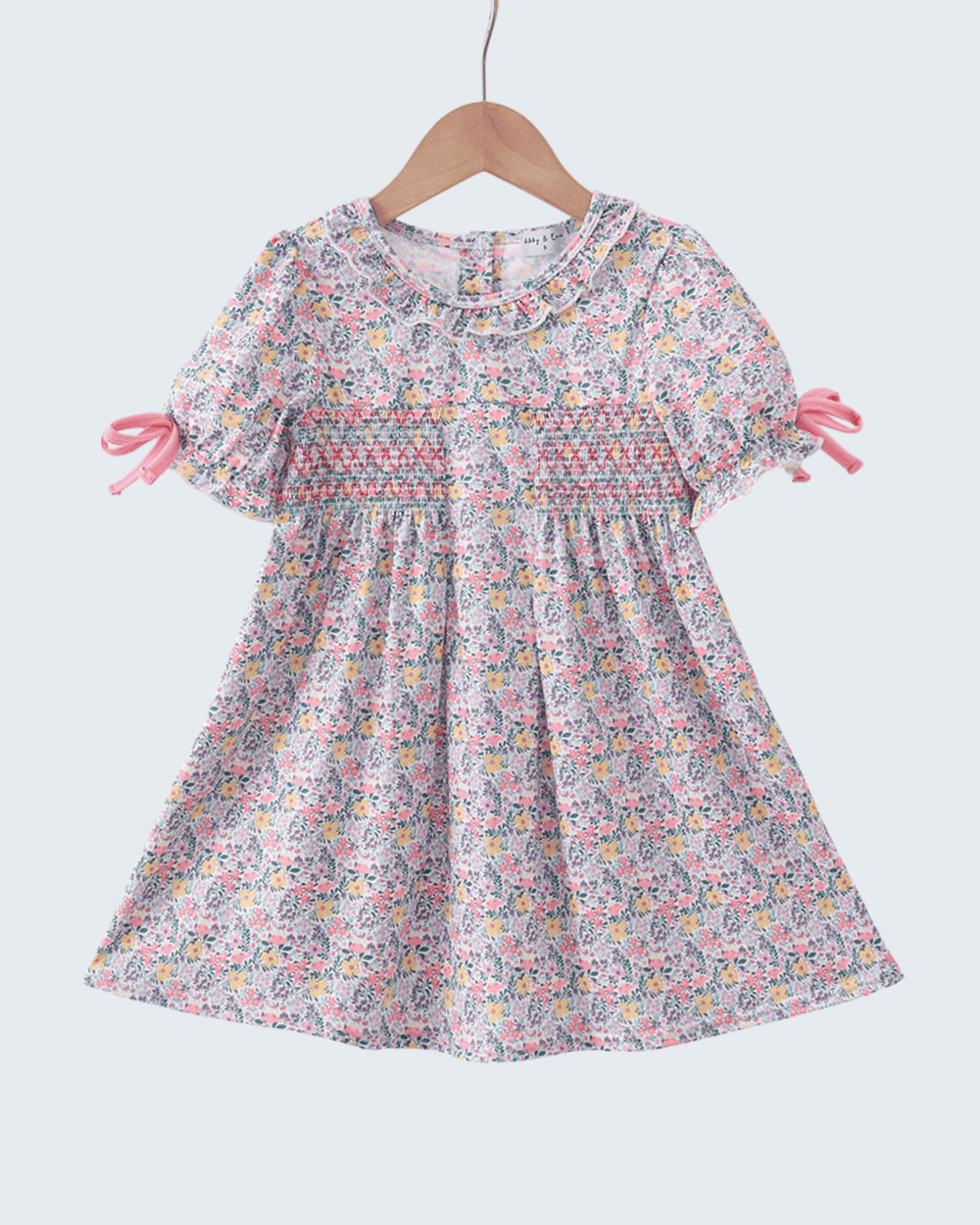 Floral dress on a hanger against a white background