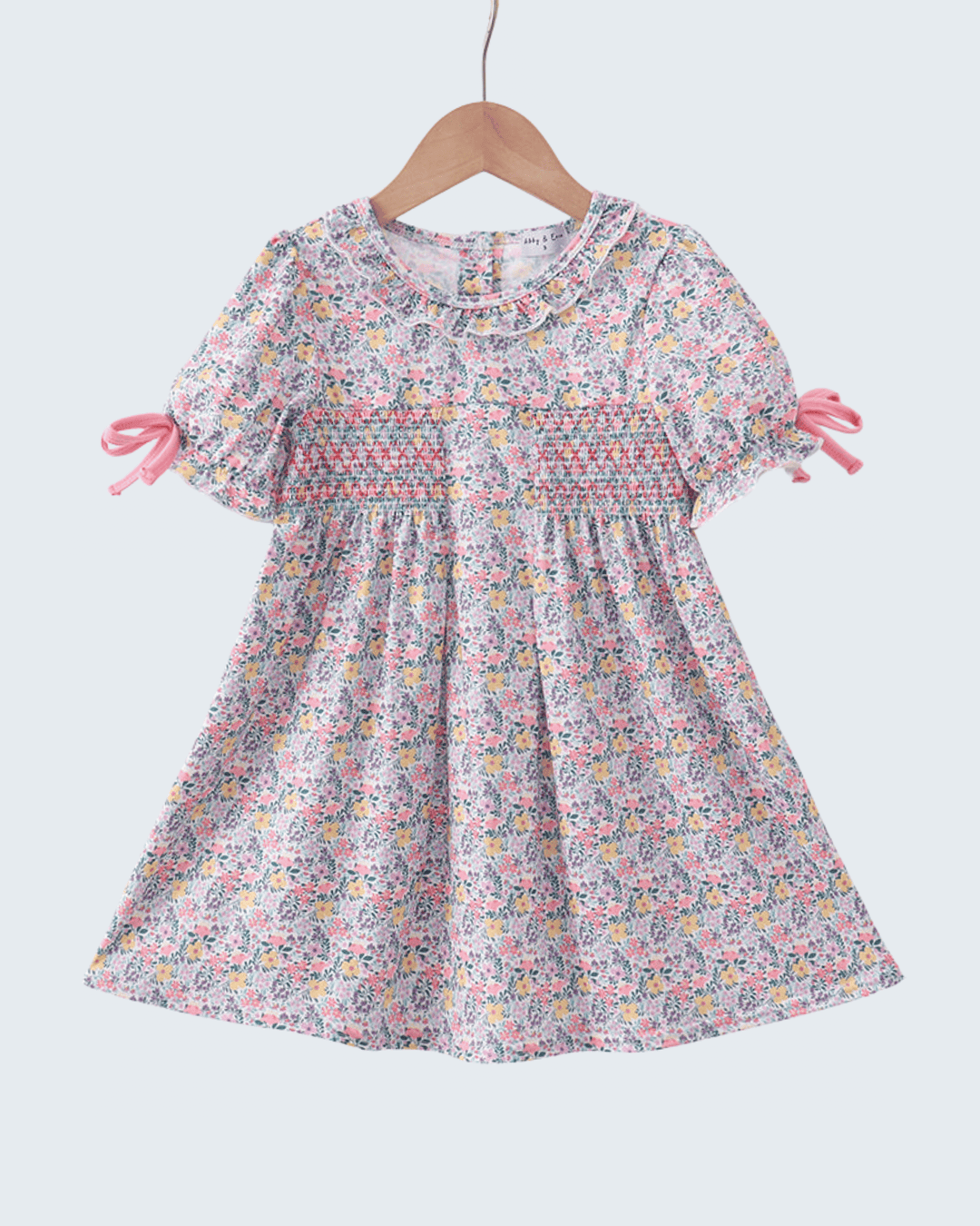 Floral dress on a hanger against a white background