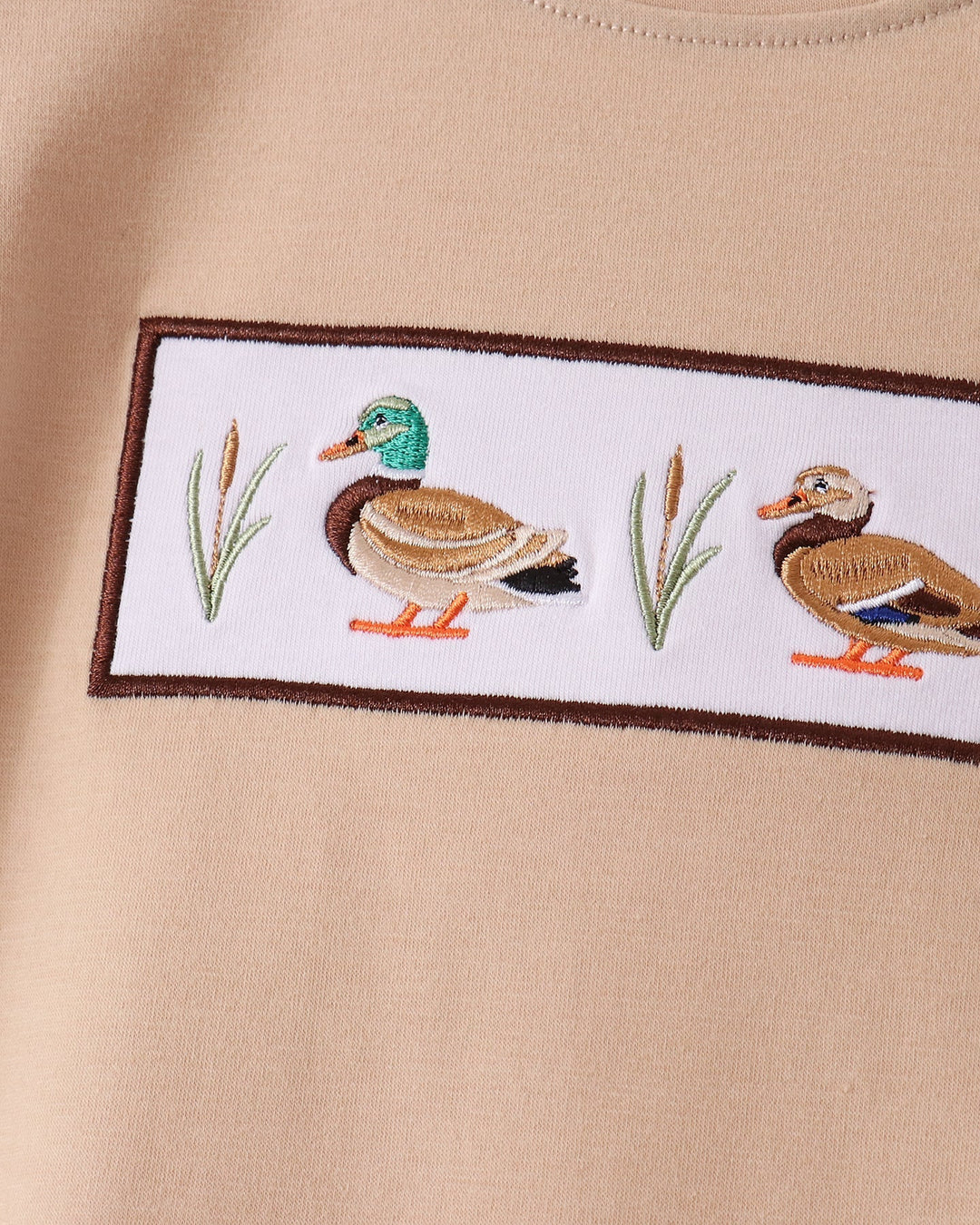 Tan shirt with rectangular duck embroidery patch along the chest