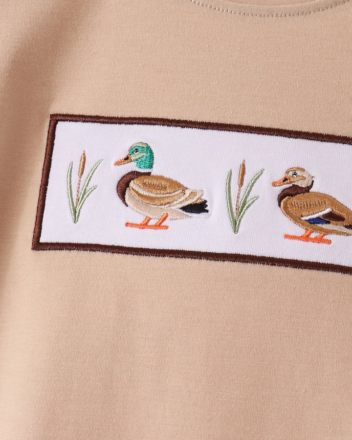 Tan shirt with rectangular duck embroidery patch along the chest