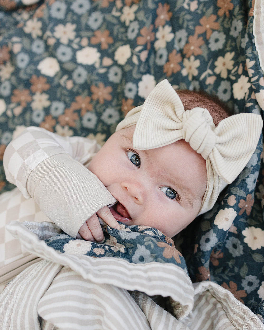 Taupe checkered head wrap with knotted bow worn on infant’s head