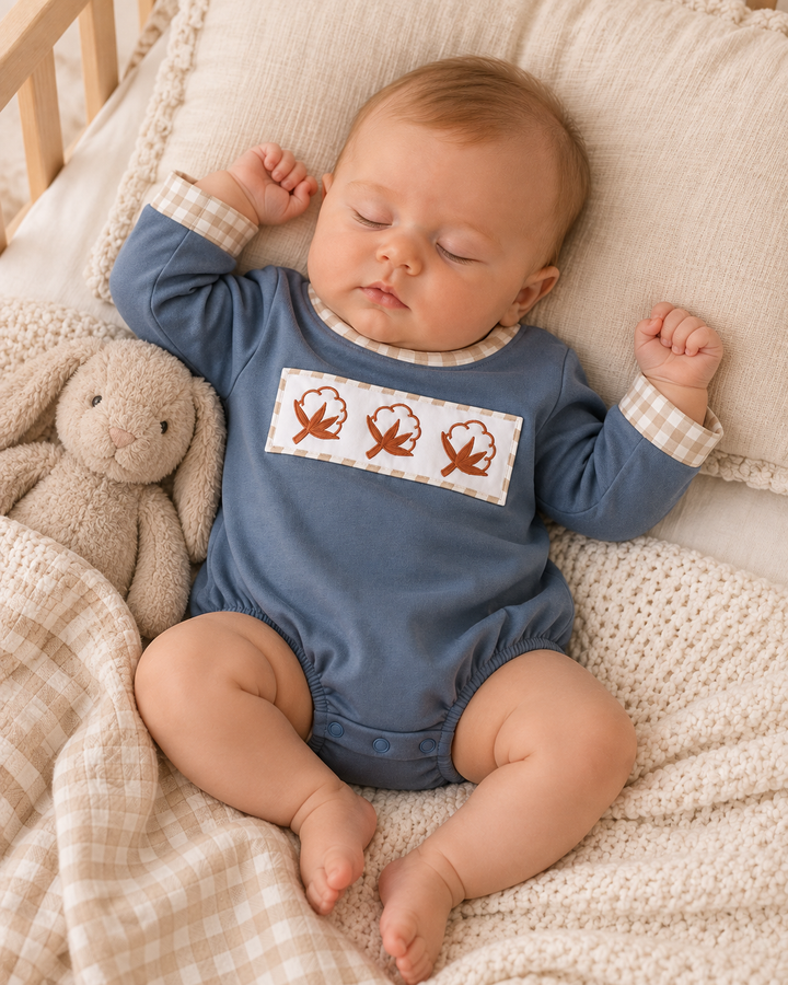 Blue cotton bubble romper with embroidered leaf panel and gingham cuffs on baby