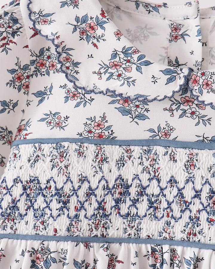 Floral smocked blouse top with blue waistband and white background, long sleeves