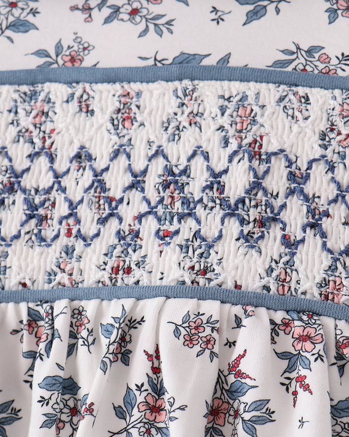 Smocked bodice blouse with gathered waist and blue floral print on white fabric