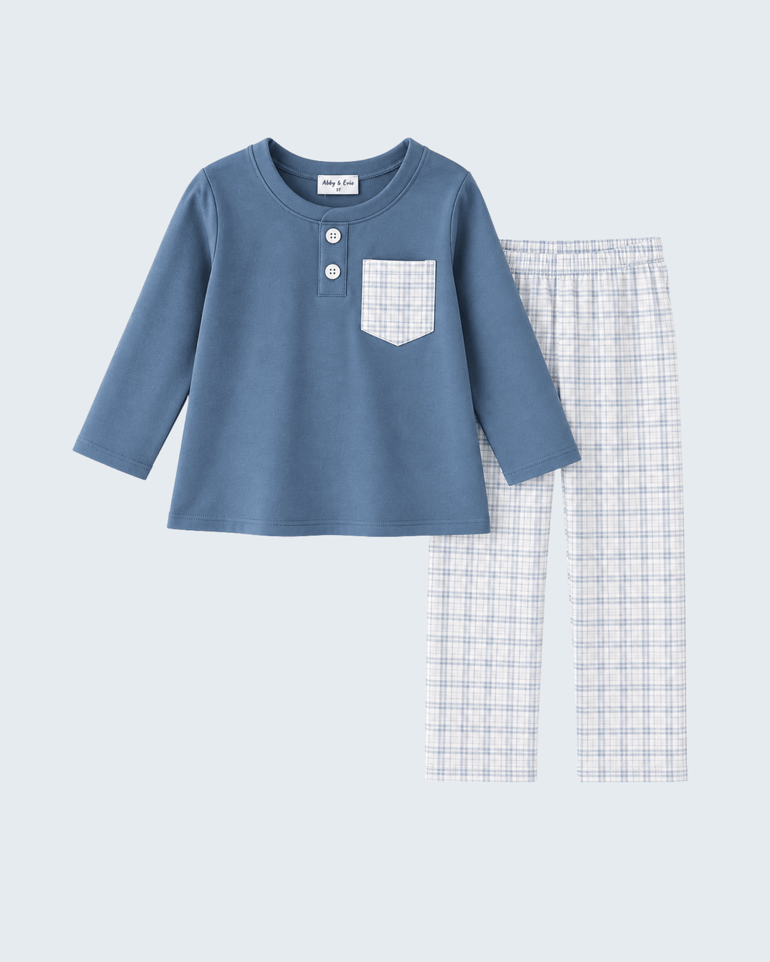 A two-piece children's pant set featuring a dusty blue long-sleeve henley top with a white plaid chest pocket and two buttons, paired with matching white and blue plaid pants, on a light gray background.