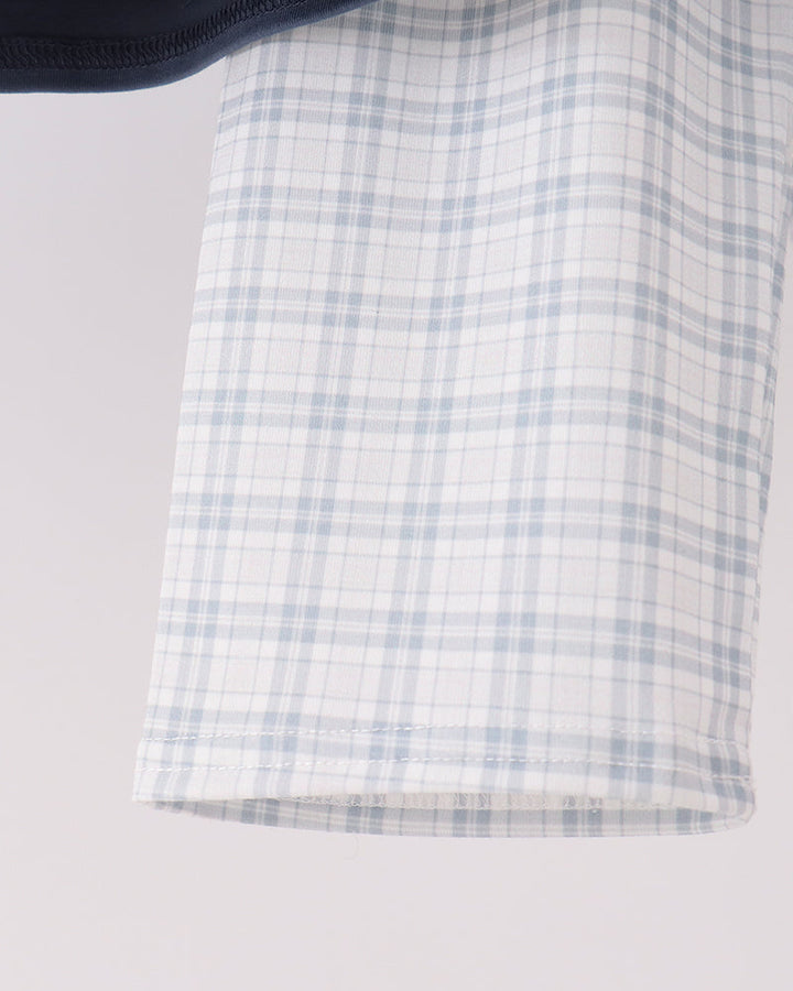 A close-up of a light blue and white plaid fabric with a dark navy trim visible at the top edge against a light gray background.