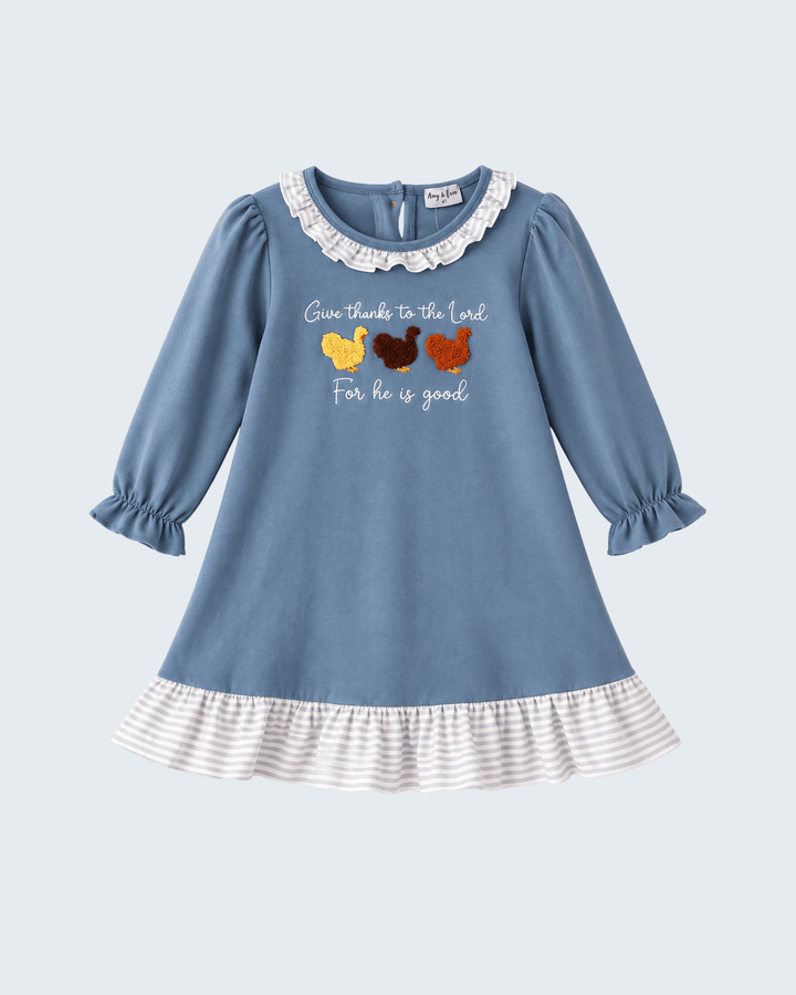 A light blue long-sleeve baby dress with a white ruffled collar, ruffled hem, and a graphic print of three chickens with the text &