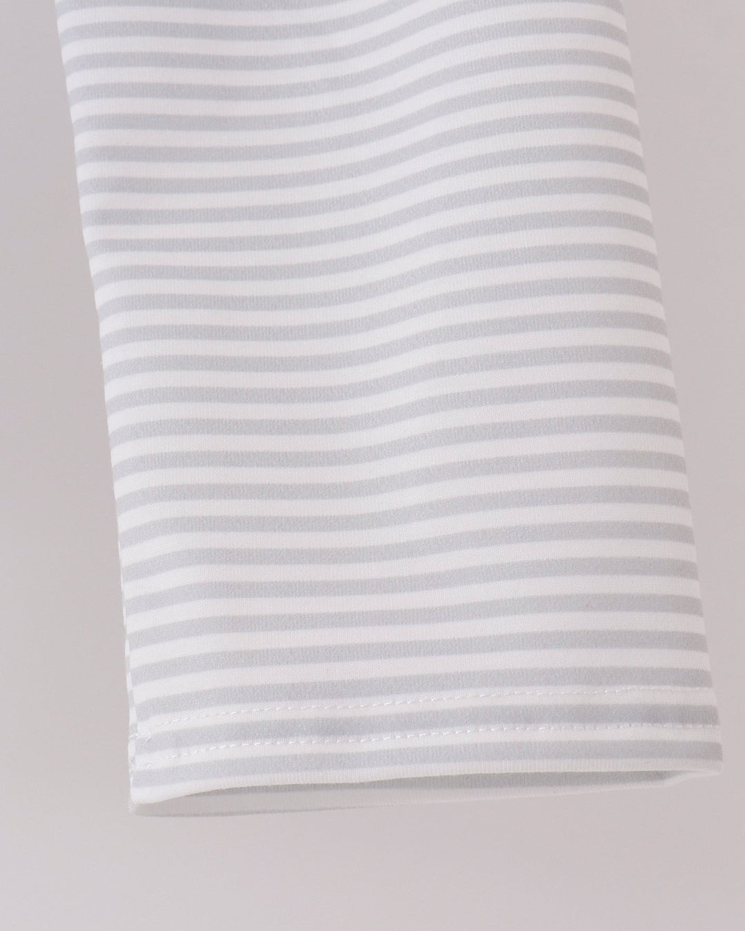 A close-up of a white fabric item, featuring thin, evenly spaced light gray horizontal stripes.