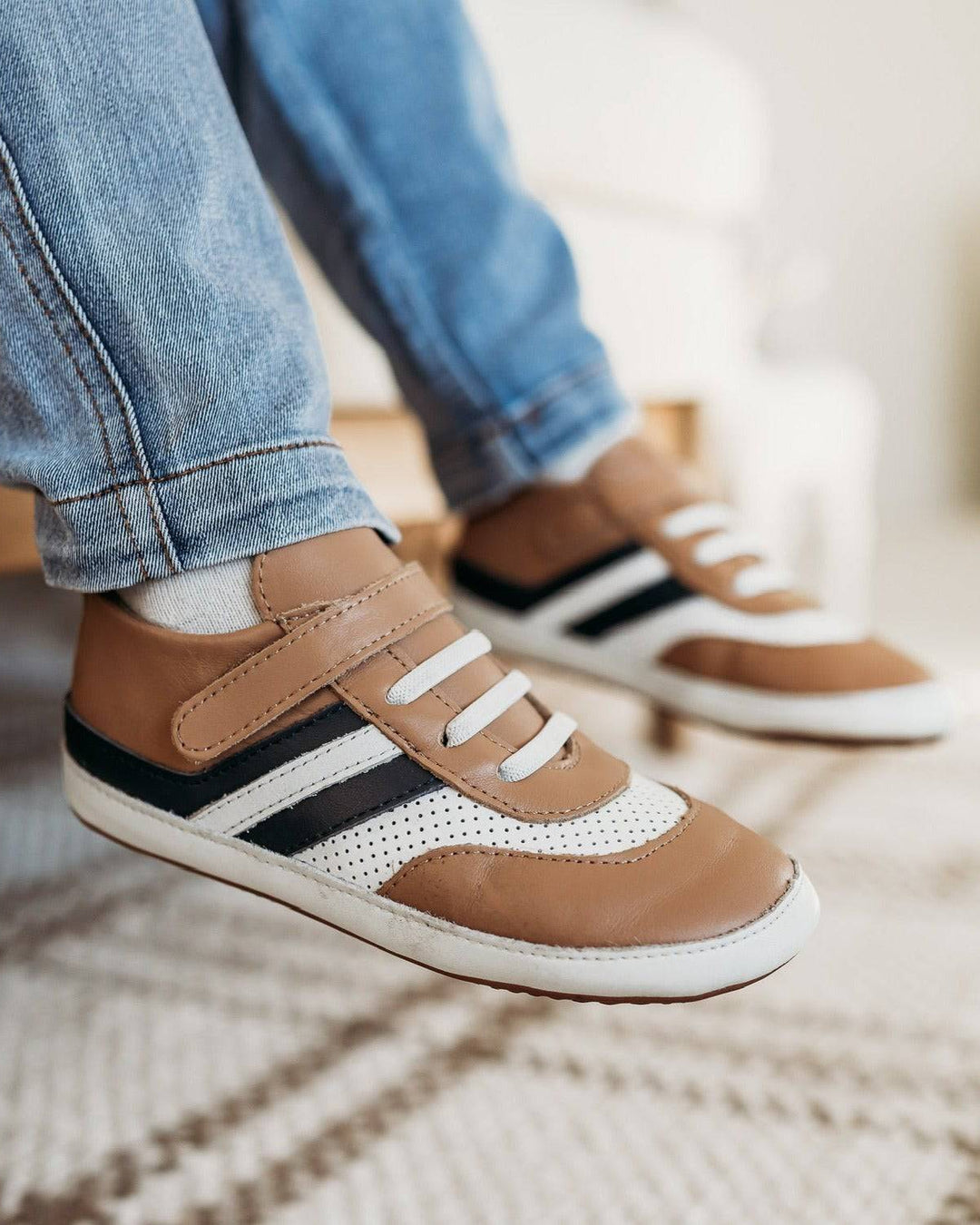 Tan and white kids sneakers with black stripe accents and velcro closure