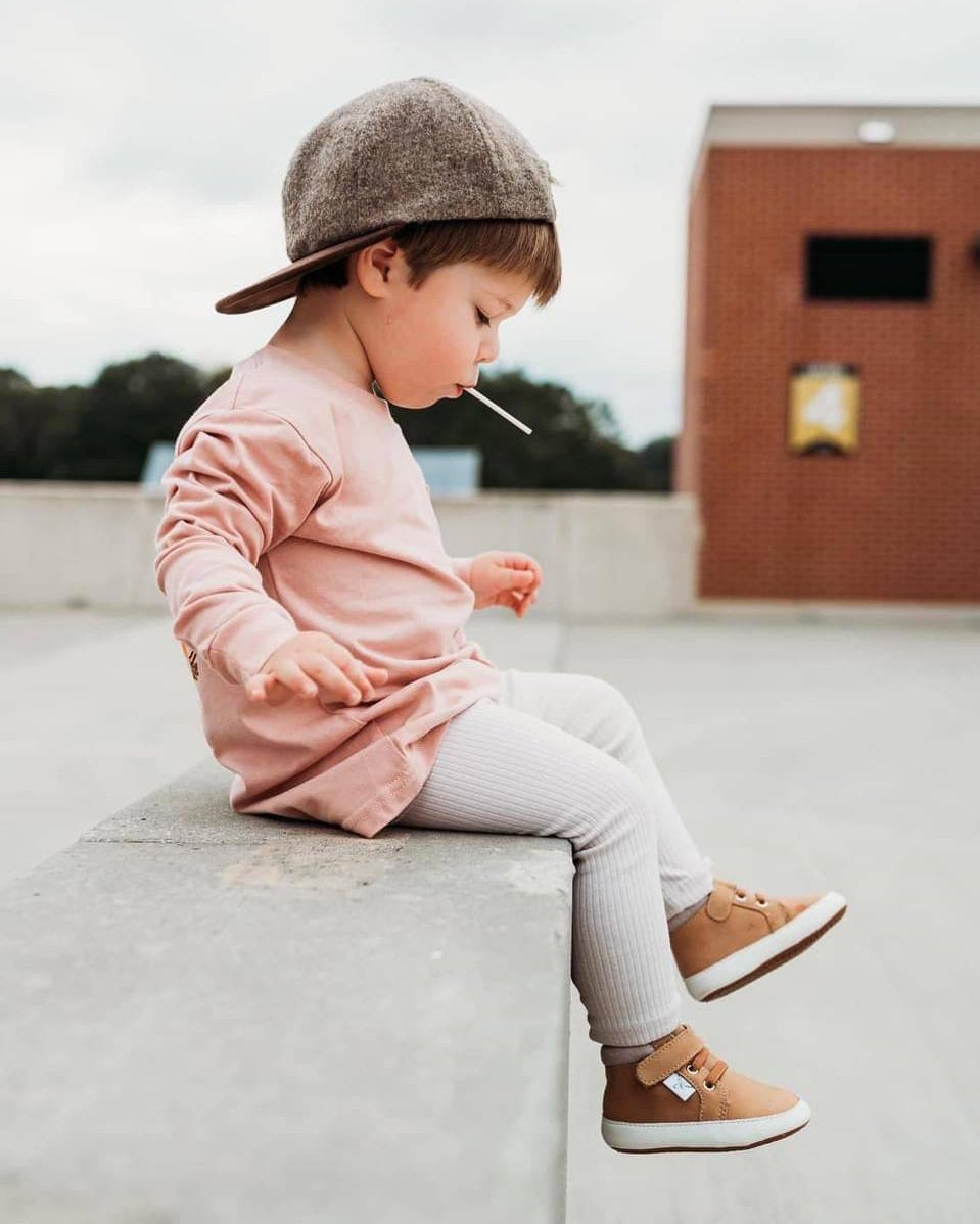 Tan high-top sneakers with hook-and-loop straps on a child’s feet
