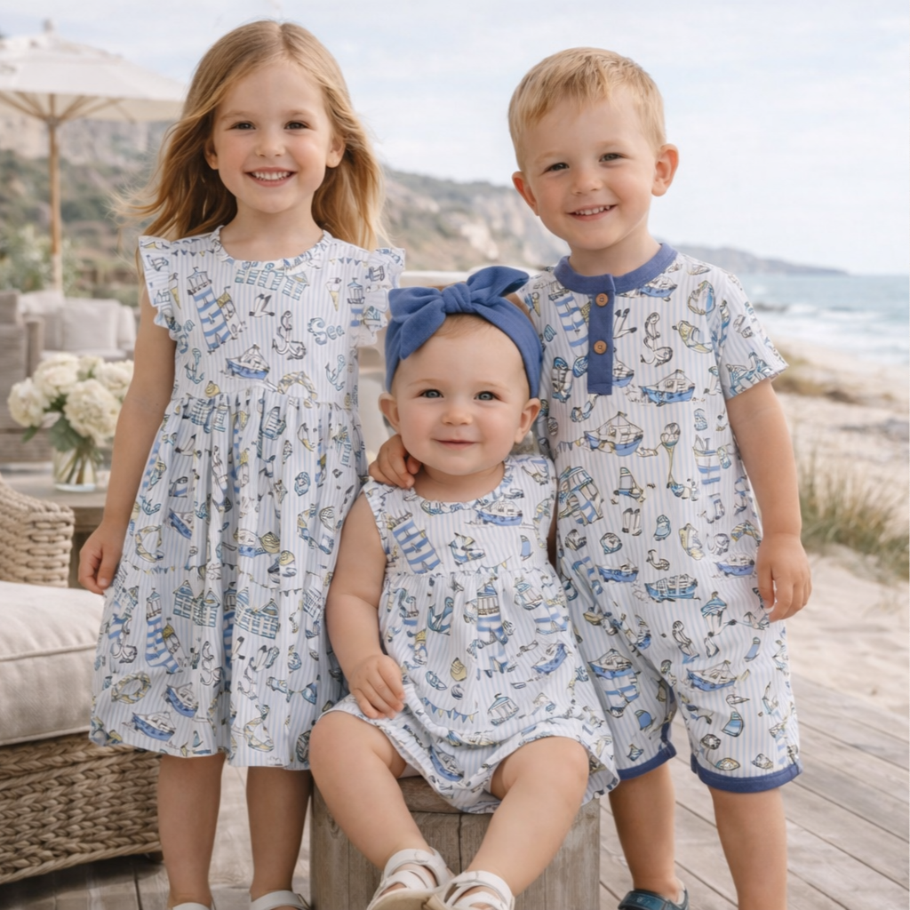 Three children in matching boutique outfits by the water