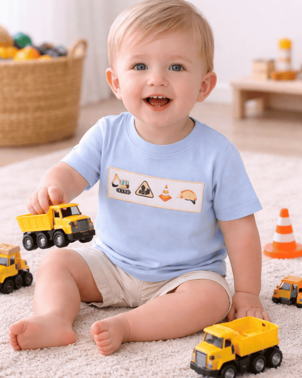 Child playing with toy trucks wearing a blue shirt with construction-themed graphics.