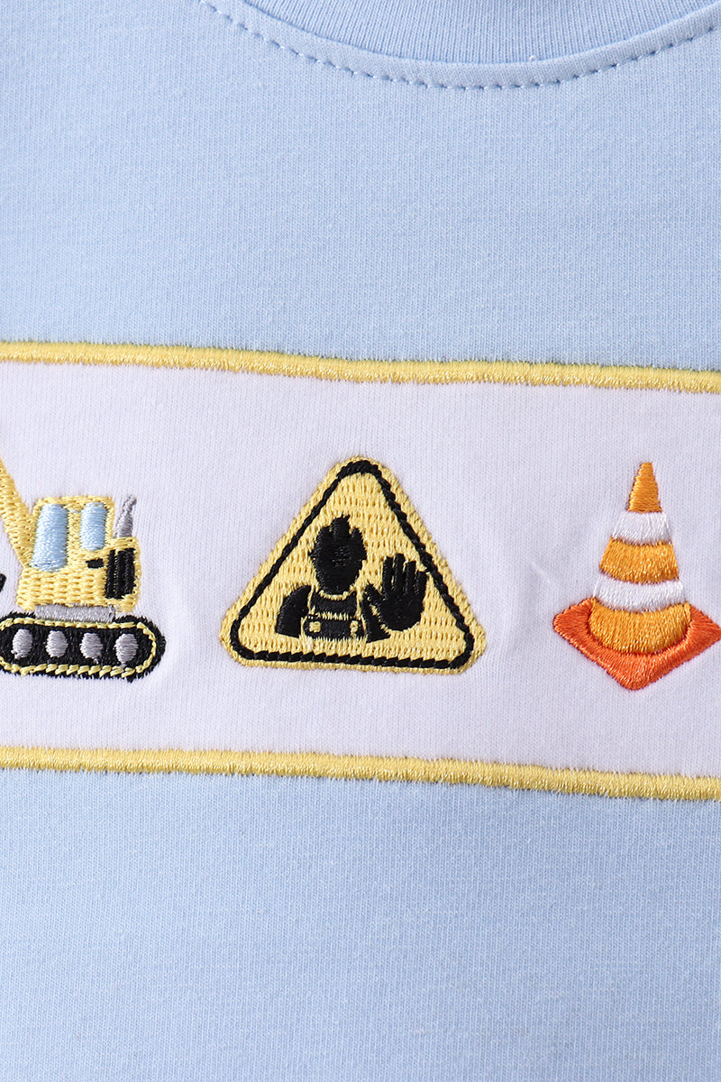 Embroidered construction-themed design on a light blue fabric.