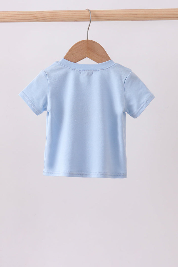 Light blue t-shirt on a wooden hanger against a light gray background