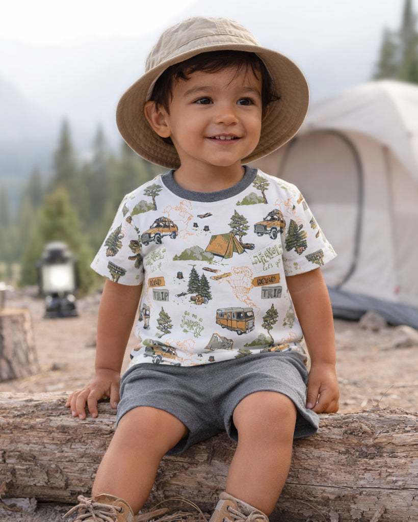 Young boy sitting  on a tree log by a tent.