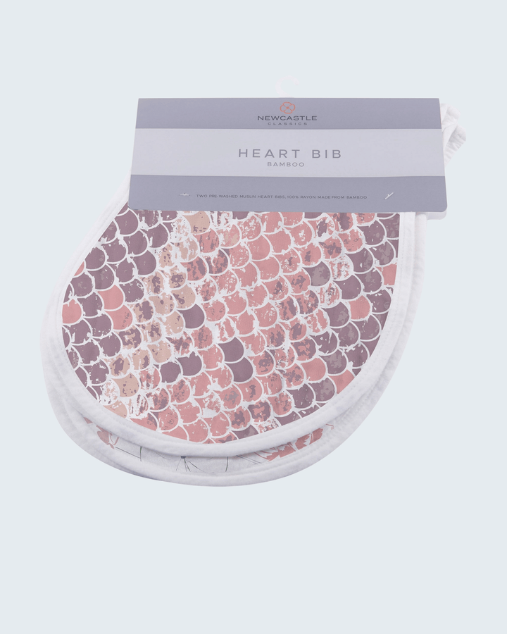 Heart-shaped bib with floral pattern in packaging on a light gray background