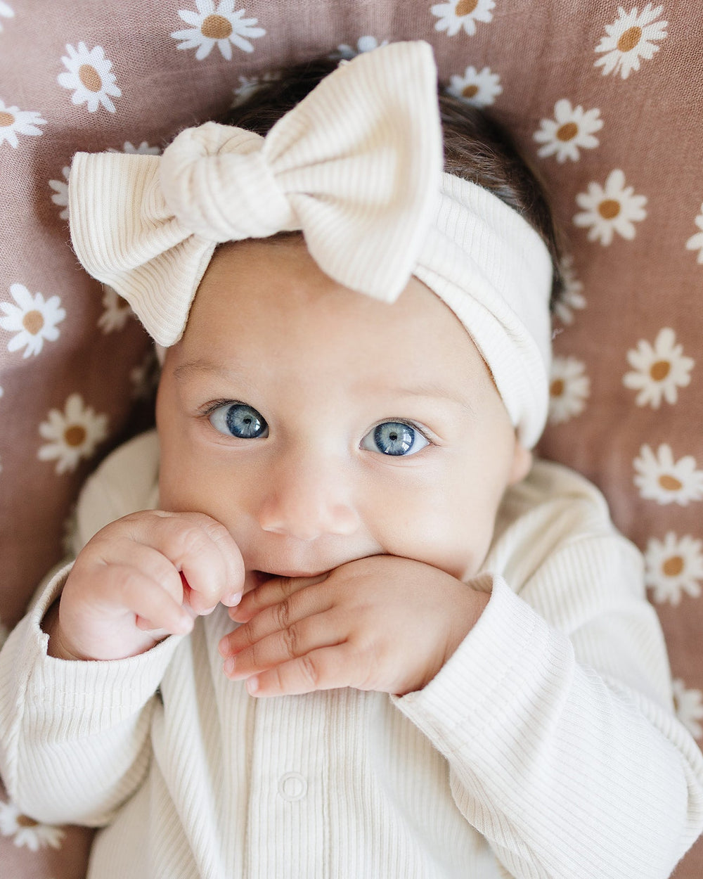 Cream ribbed head wrap with knotted bow, worn on a baby's head