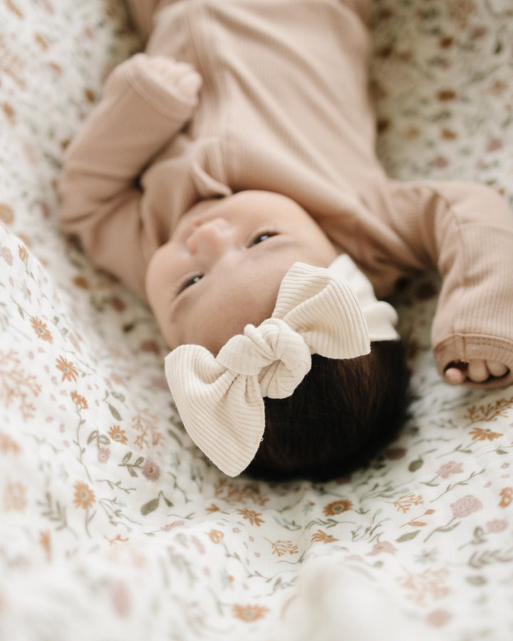 Cream ribbed head wrap with knotted bow, baby lying down