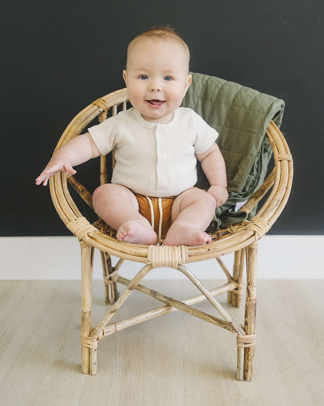 Baby sitting in a wicker chair with a dark background