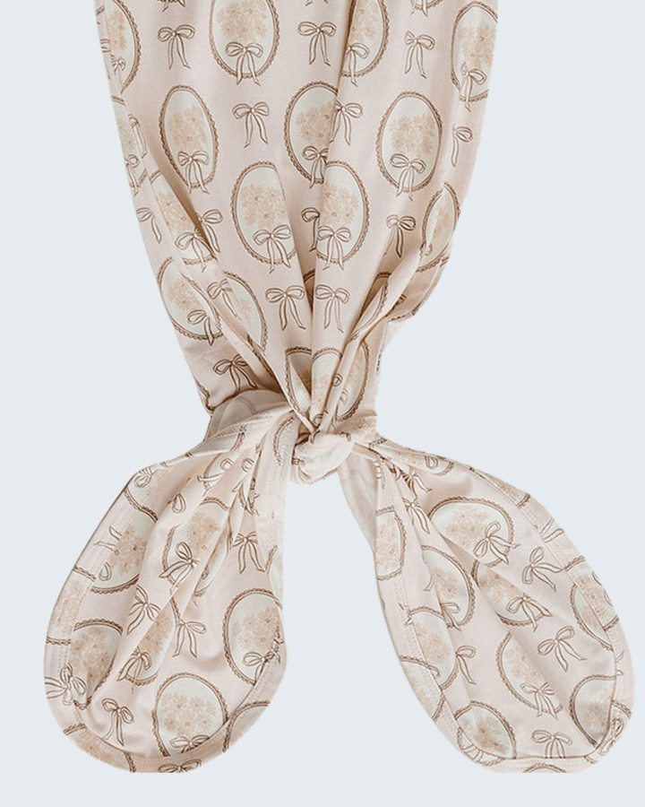 Bamboo knot gown with tied center bow and long fabric tails, light tan bow-print pattern