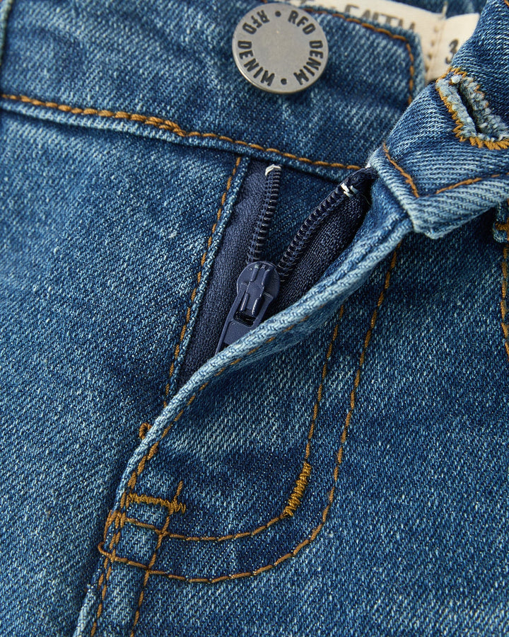 Blue denim jeans close-up: front yoke seam, belt loops, zipper