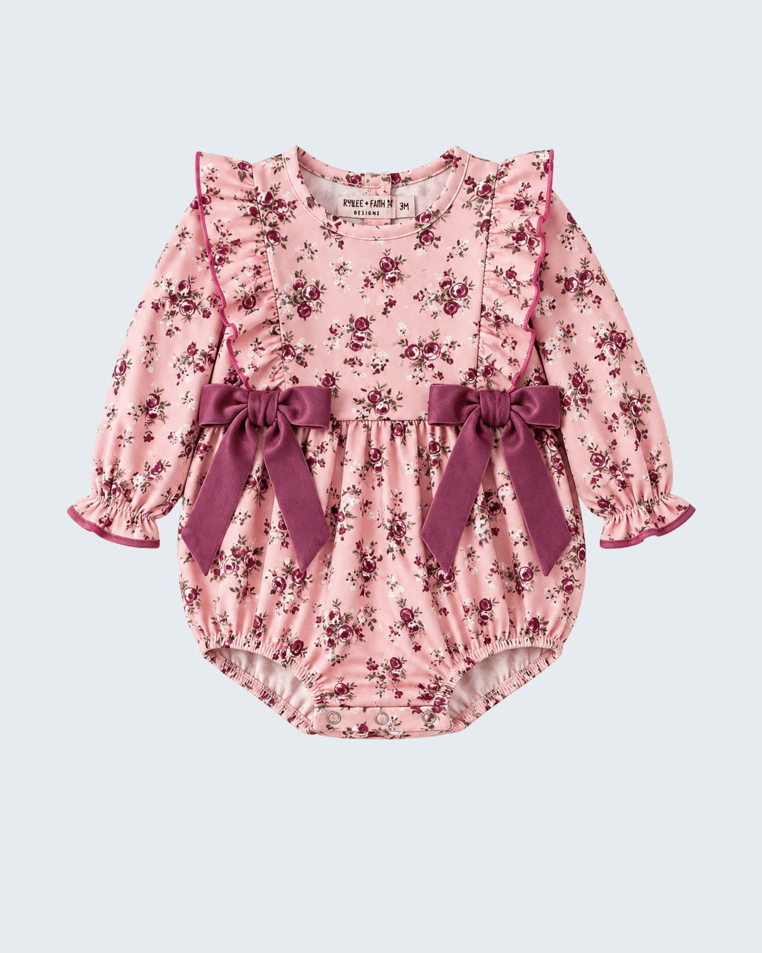 Floral pink baby romper with long sleeves, ruffled cuffs, and plum bow waist