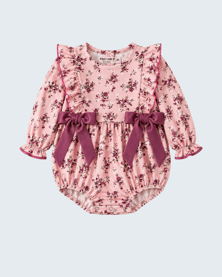 Floral pink baby romper with long sleeves, ruffled cuffs, and plum bow waist