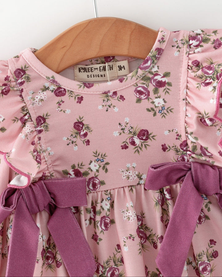 Pink floral romper close-up with ruffle collar and purple front bows