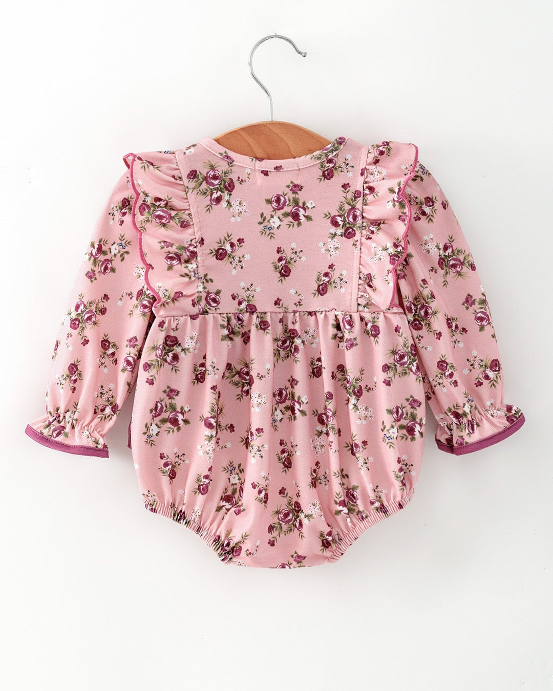 Pink floral baby romper with long sleeves and purple bow at front