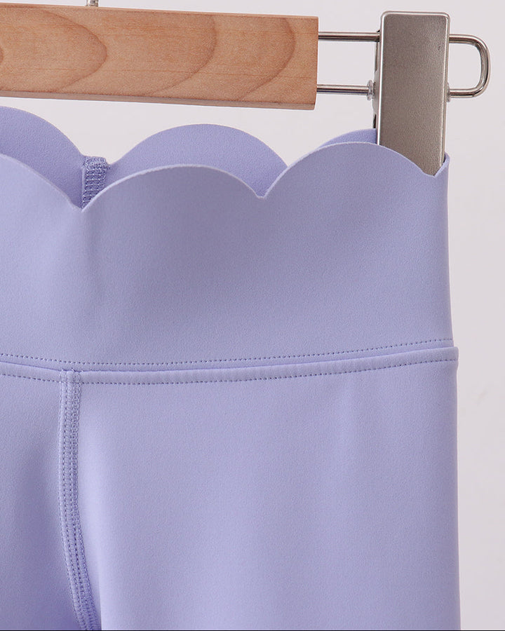 Light purple leggings on a wooden hanger against a white background