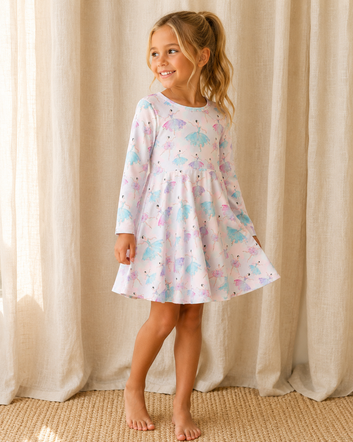 Young girl wearing a patterned dress standing in front of beige curtains.