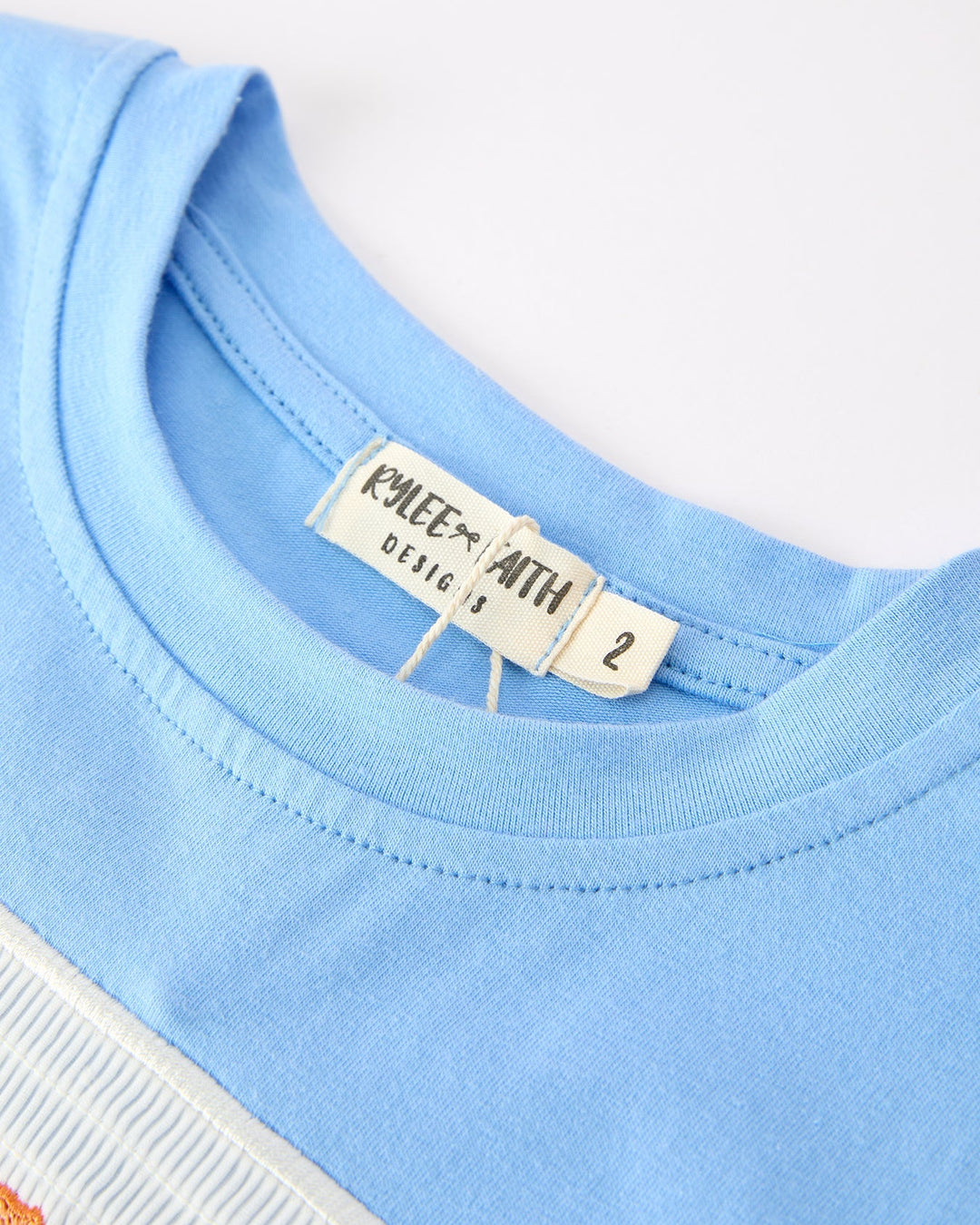 Close-up of a blue t-shirt with a brand label on a white background