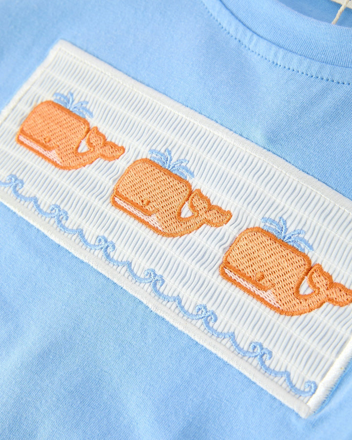 Embroidered design of whales on a light blue fabric