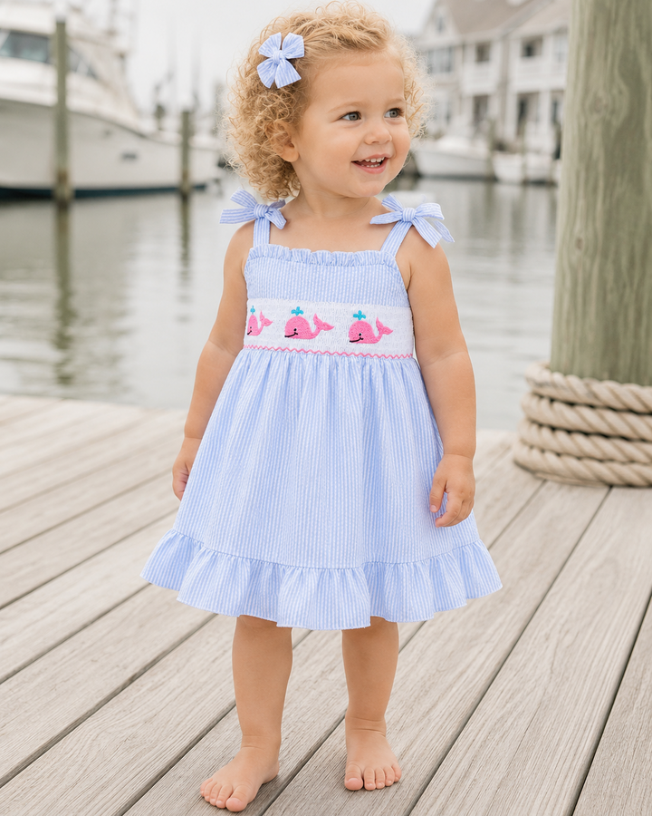 Toddler girl in blue seersucker dress with whale embroidery