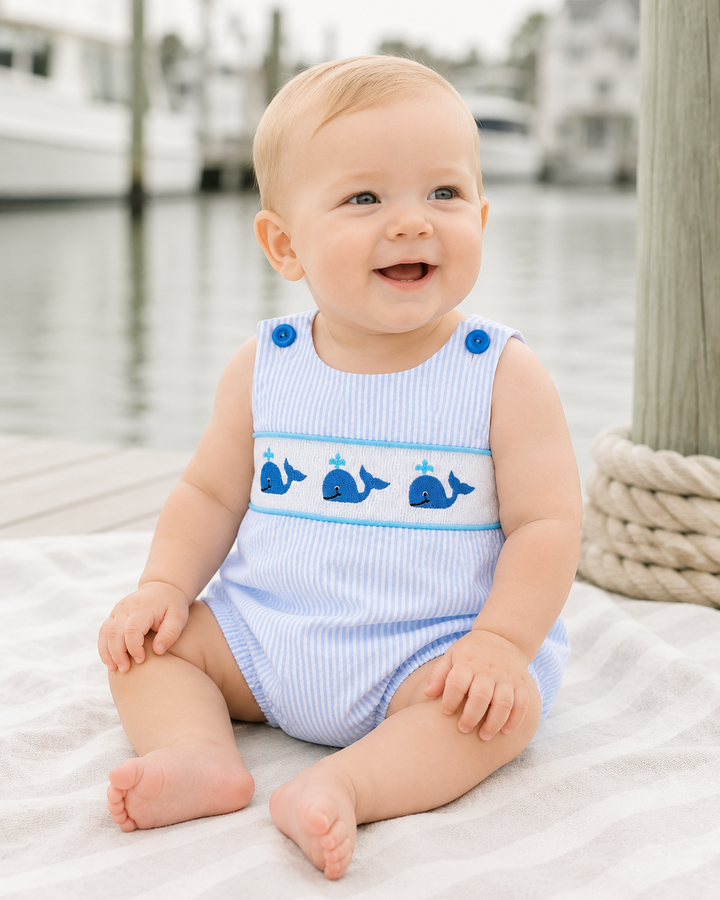 Baby boy in whale embroidered romper by harbor